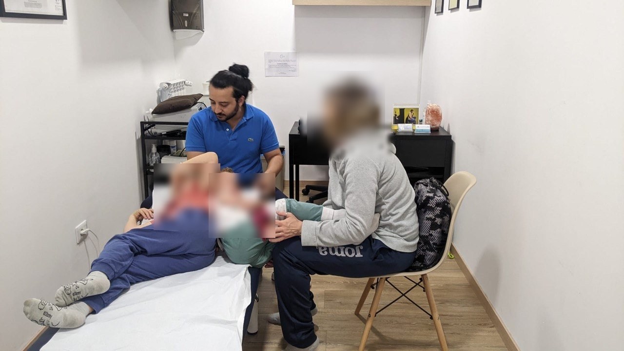 Trattamento osteopatico pediatrico in studio, volti oscurati per privacy